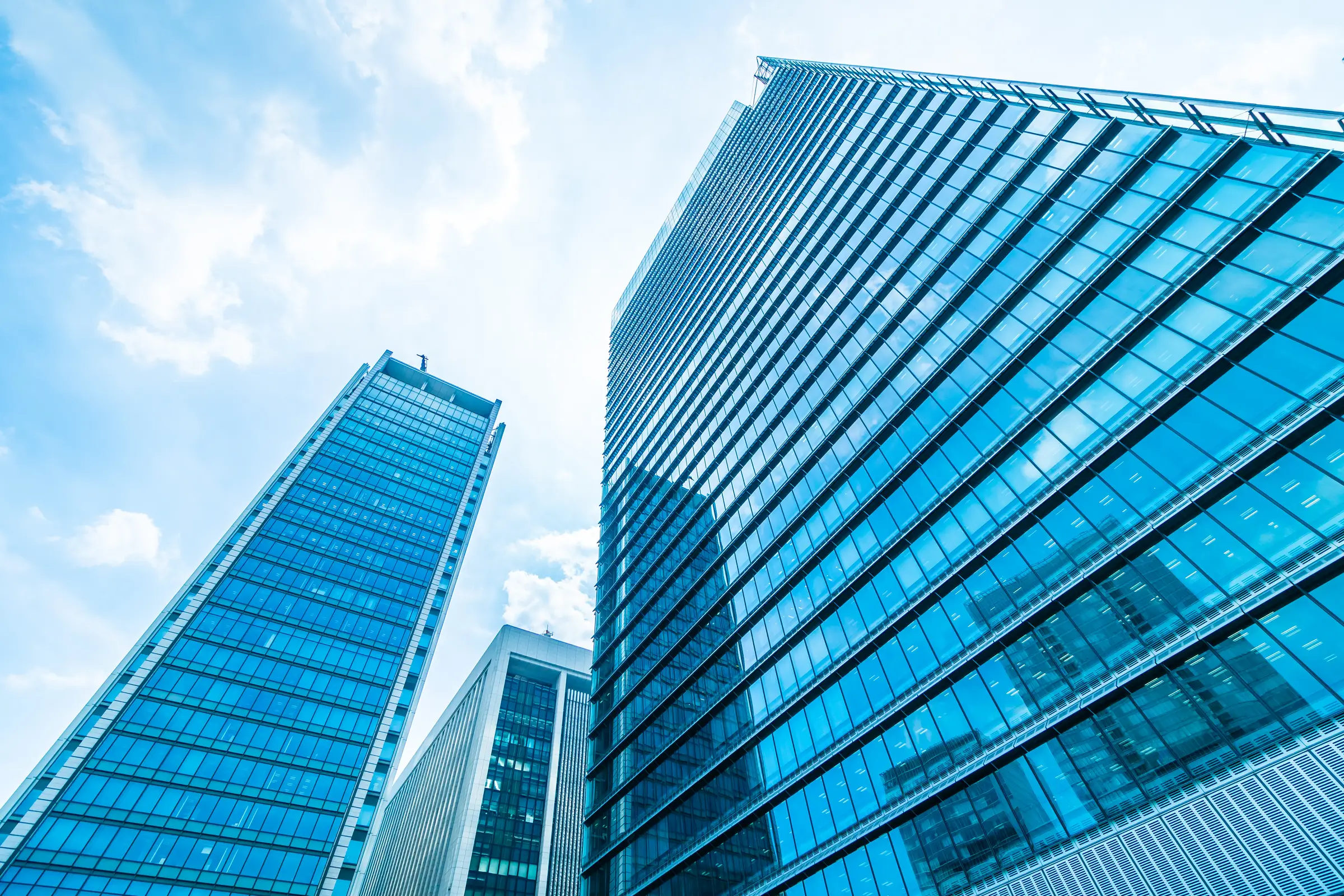 Low-angle view of glass office skyscrapers against a blue sky